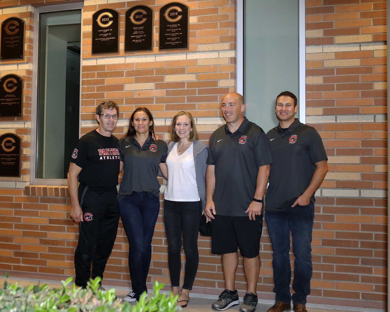 Five inductees pose in front of the Hall of Fame plaque.