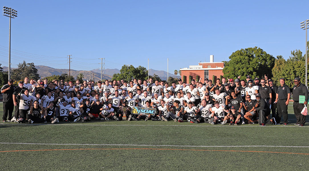 Each player and coach holds up the number 1 in a team photo.