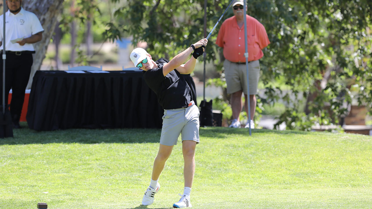 A male golfer hits a tee shot.