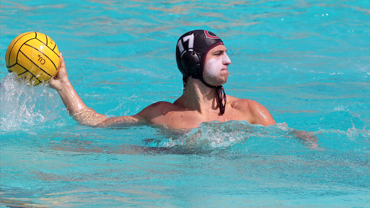 Jacob Bullock reaches back to throw a water polo ball.