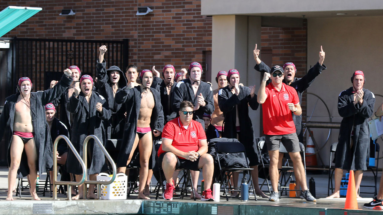 The men's water polo bench celebrates a goal.