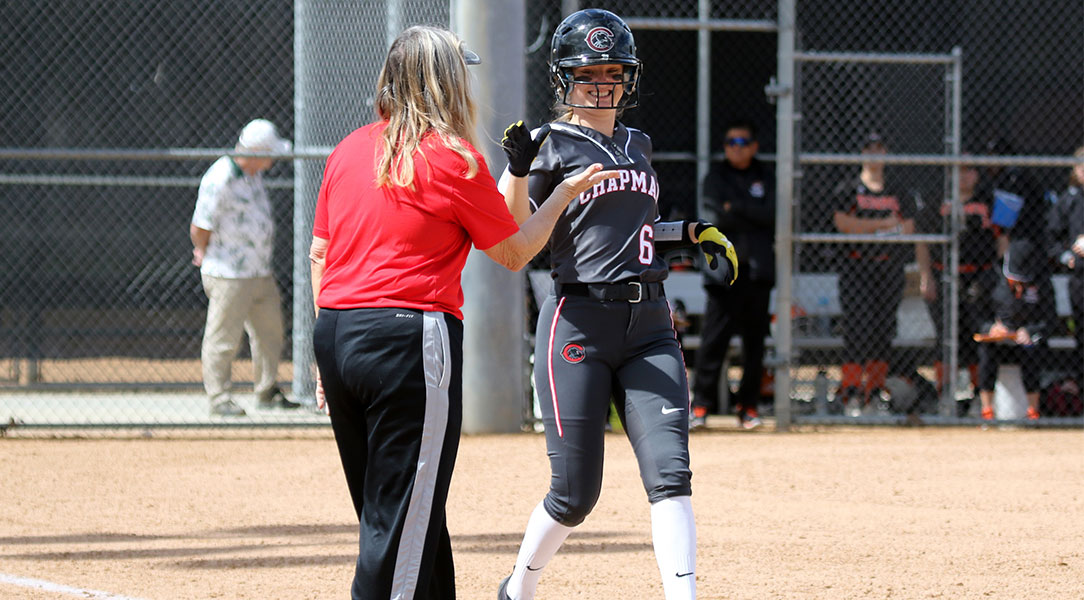 Michaela Foisy high-fives her coach at first base.