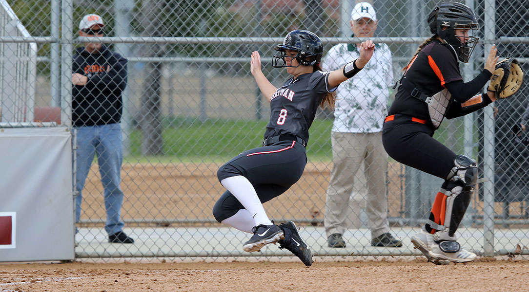 Samantha Whalen dives across home plate to score a run.