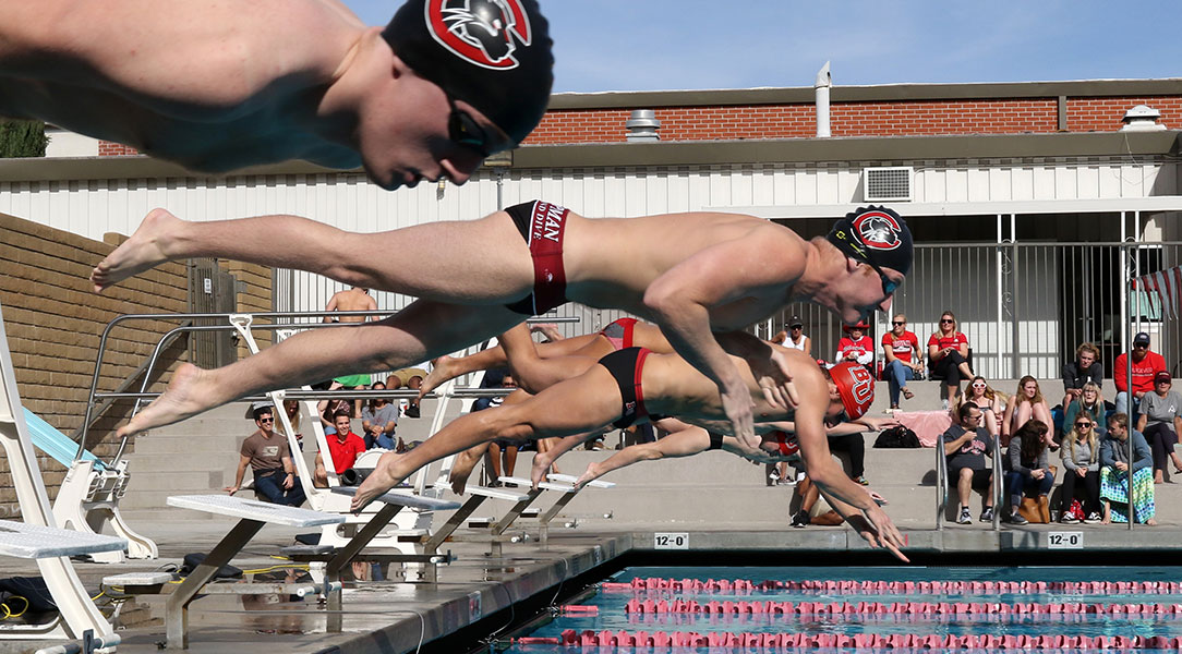 Members of the men's swim team jump into the pool.