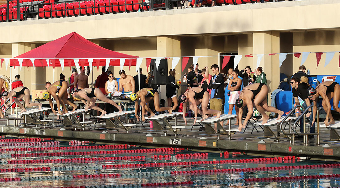 Women's swimmers get ready on the blocks.