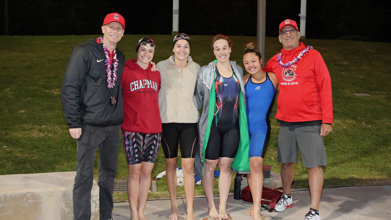 The women's relay team stands with the coaches.