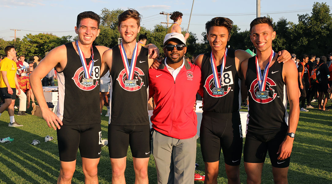 The relay team and Coach Woods standing together.