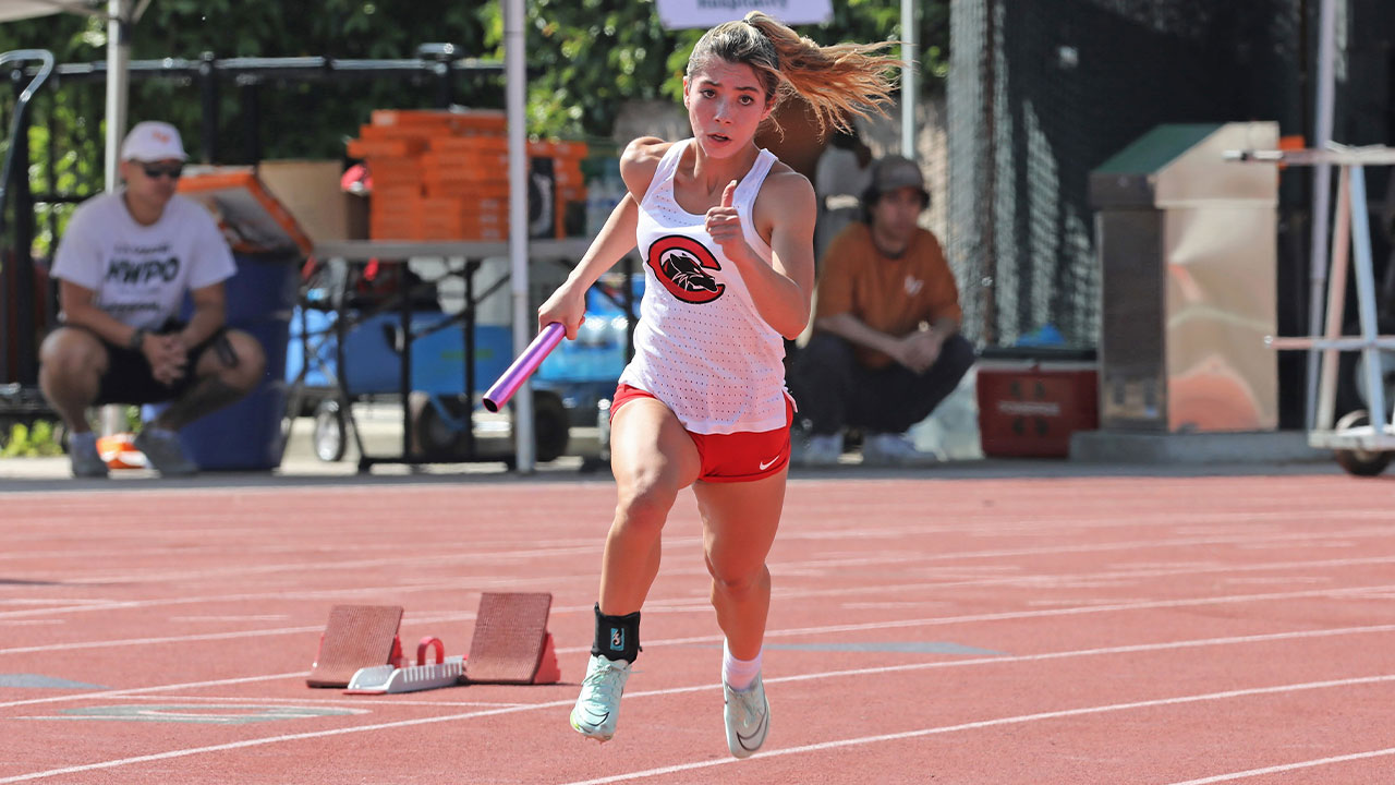 Makenna Lizarde runs around the track with the baton.