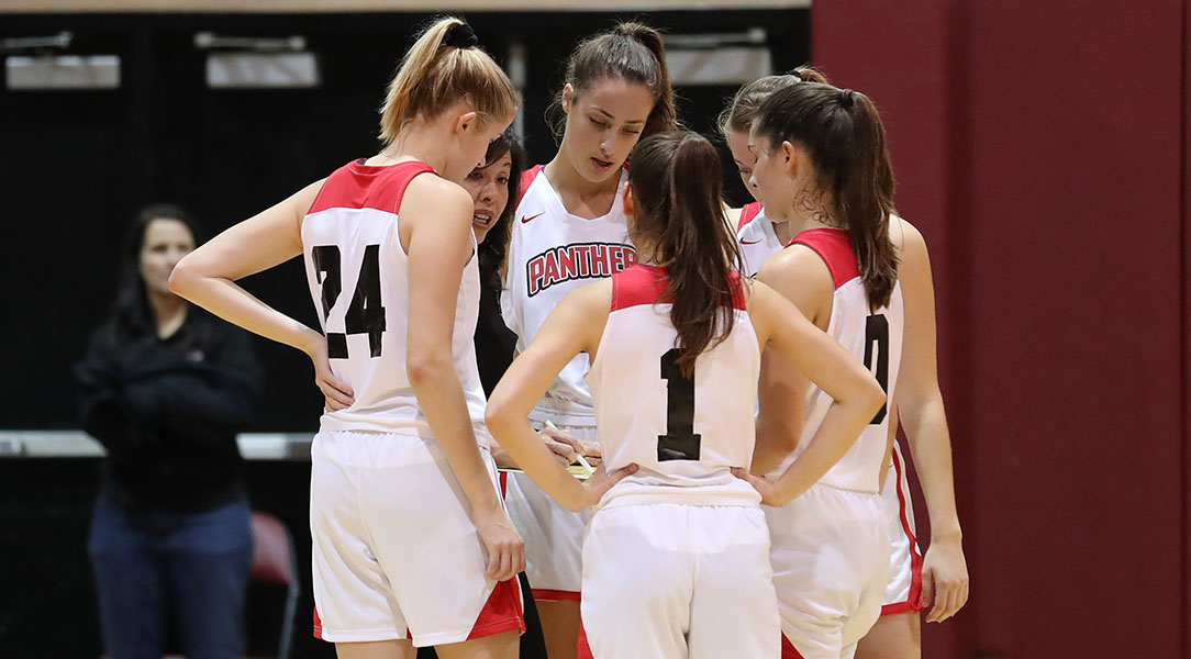 Five players huddle around Coach Jue.