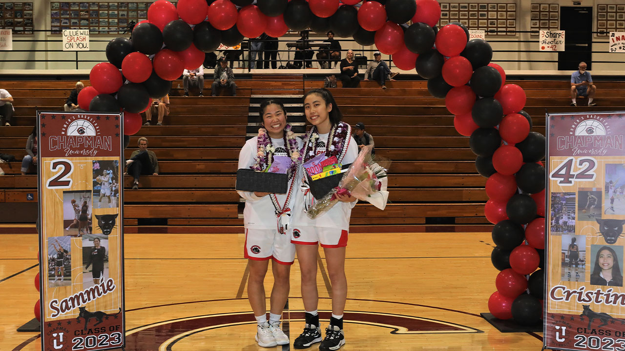 Basketball seniors Sammie Inana and Cristin Lue under a balloon arch at midcourt.