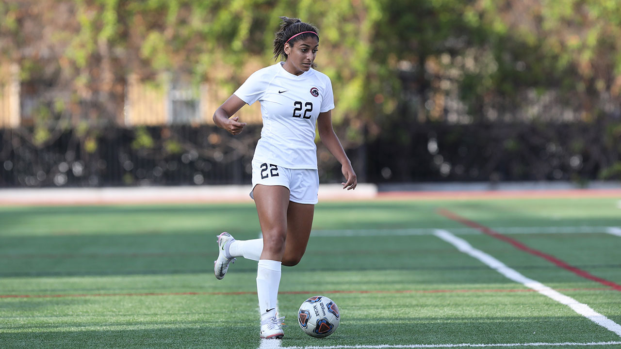 Nikki Namdar dribbles a soccer ball while running.