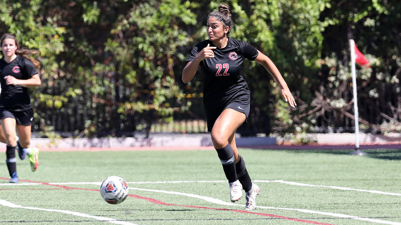 Nikki Namdar dribbles a soccer ball while running.