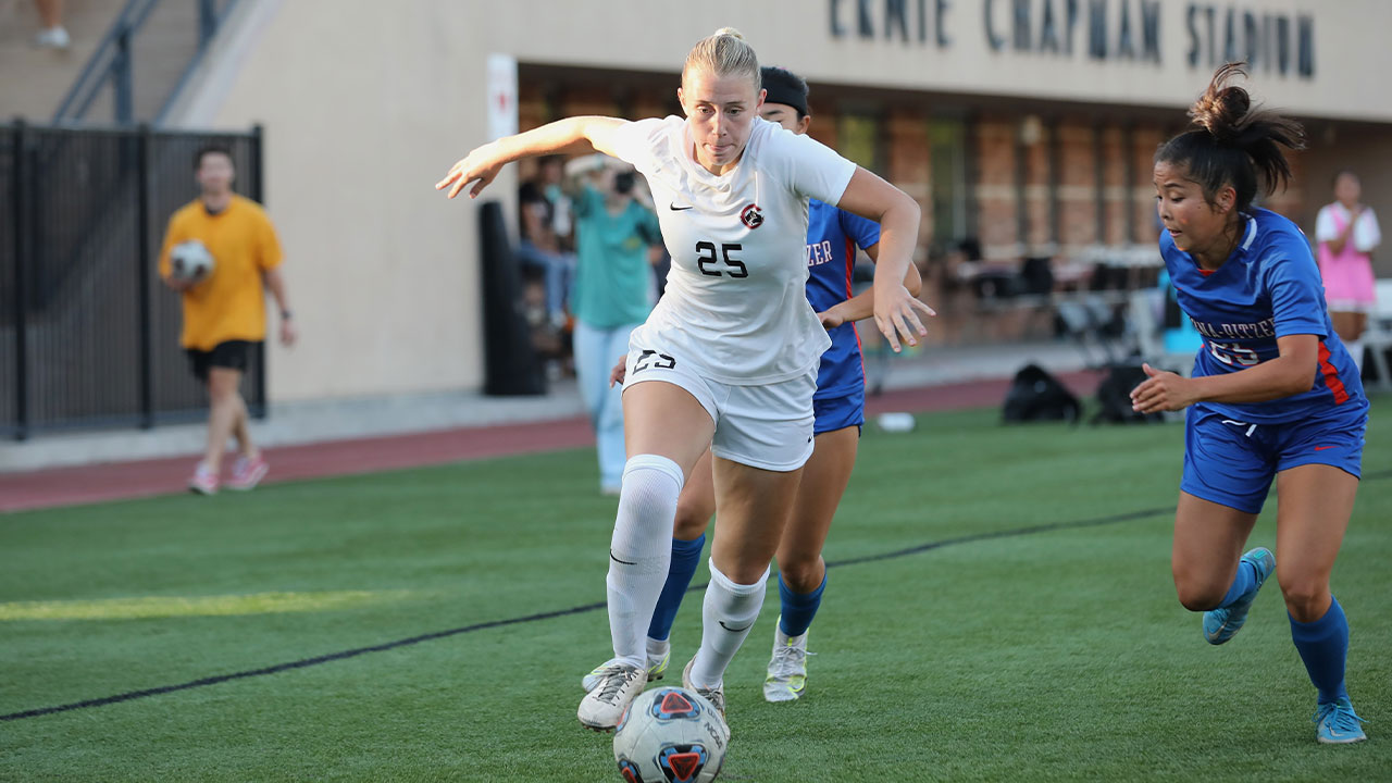 Stella Bauman dribbles the soccer ball around two defenders.